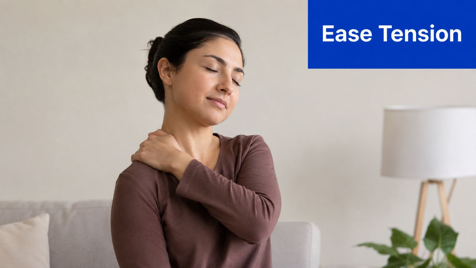 A woman with her eyes closed holding her shoulder to relieve neck and muscle tension at home.