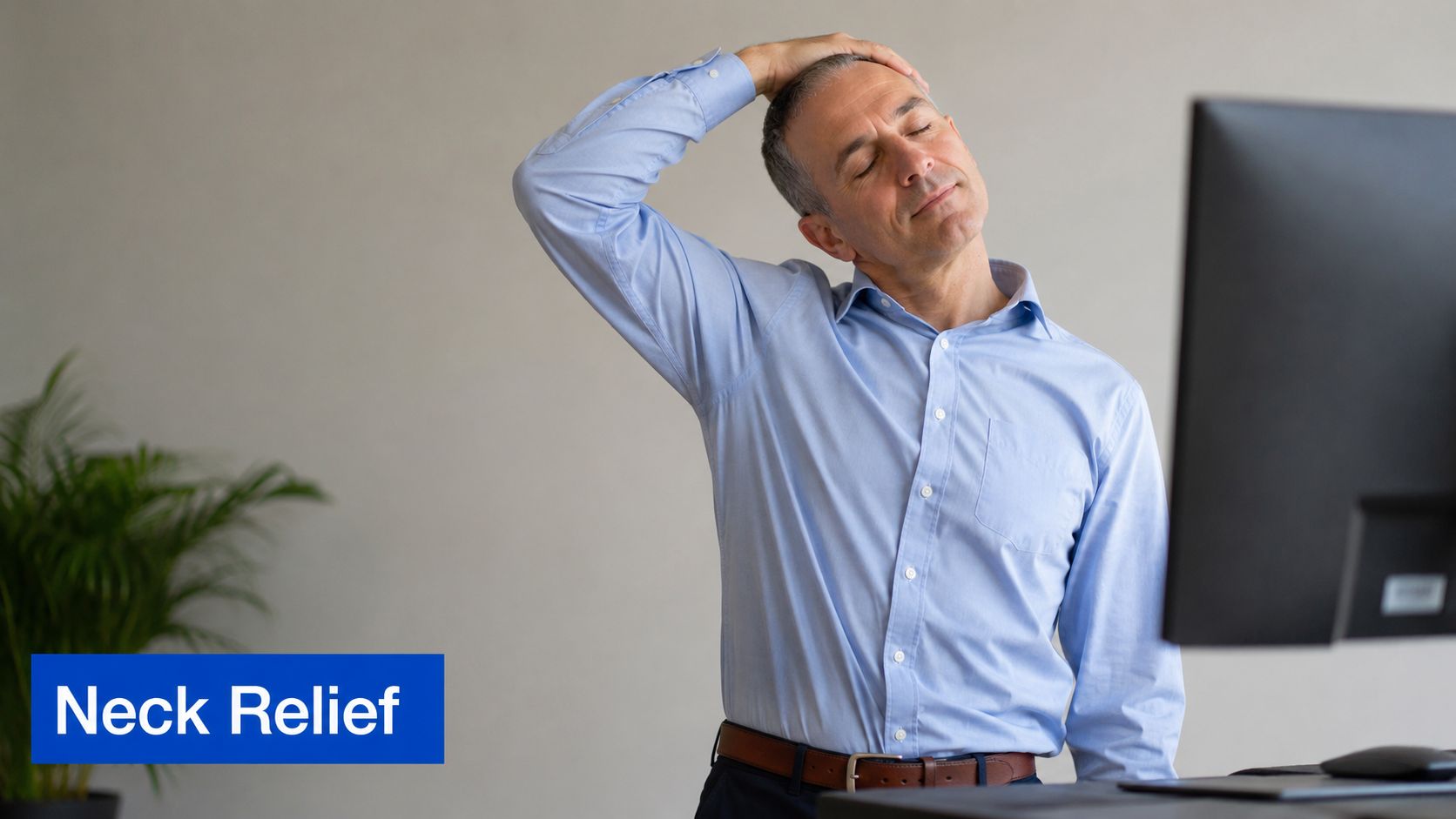 A professional man at a standing desk performing a gentle neck stretch for relief while working.