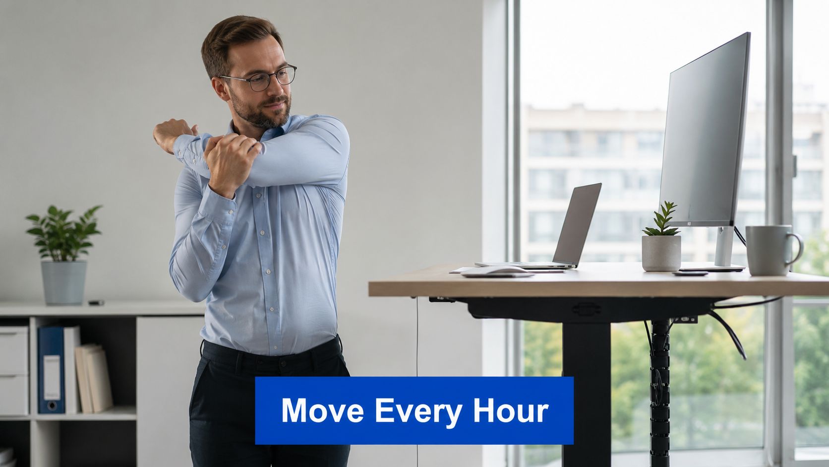 A professional man stretching his arm while standing at his adjustable standing desk in a modern office.