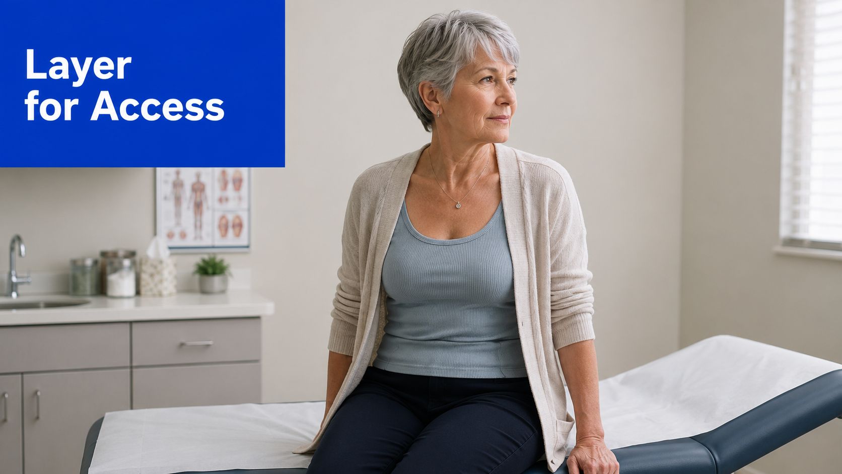 A mature woman sitting on an examination table in a clinical office setting, wearing comfortable layered clothing.