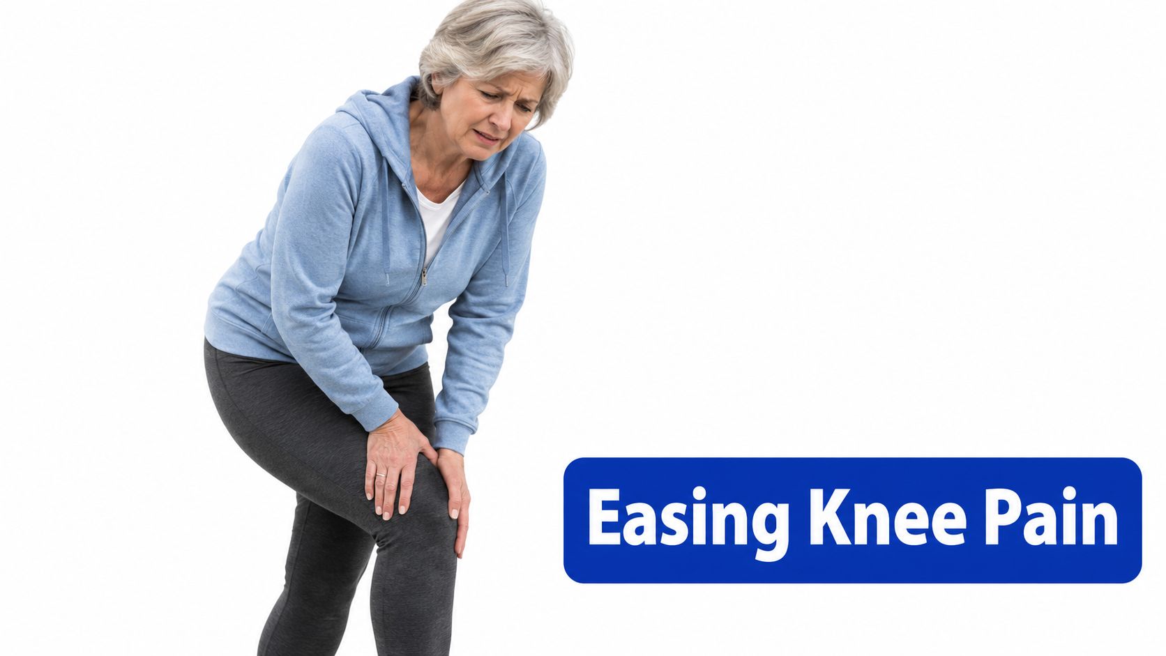 An older woman in a blue hoodie standing and holding her knee while experiencing pain.